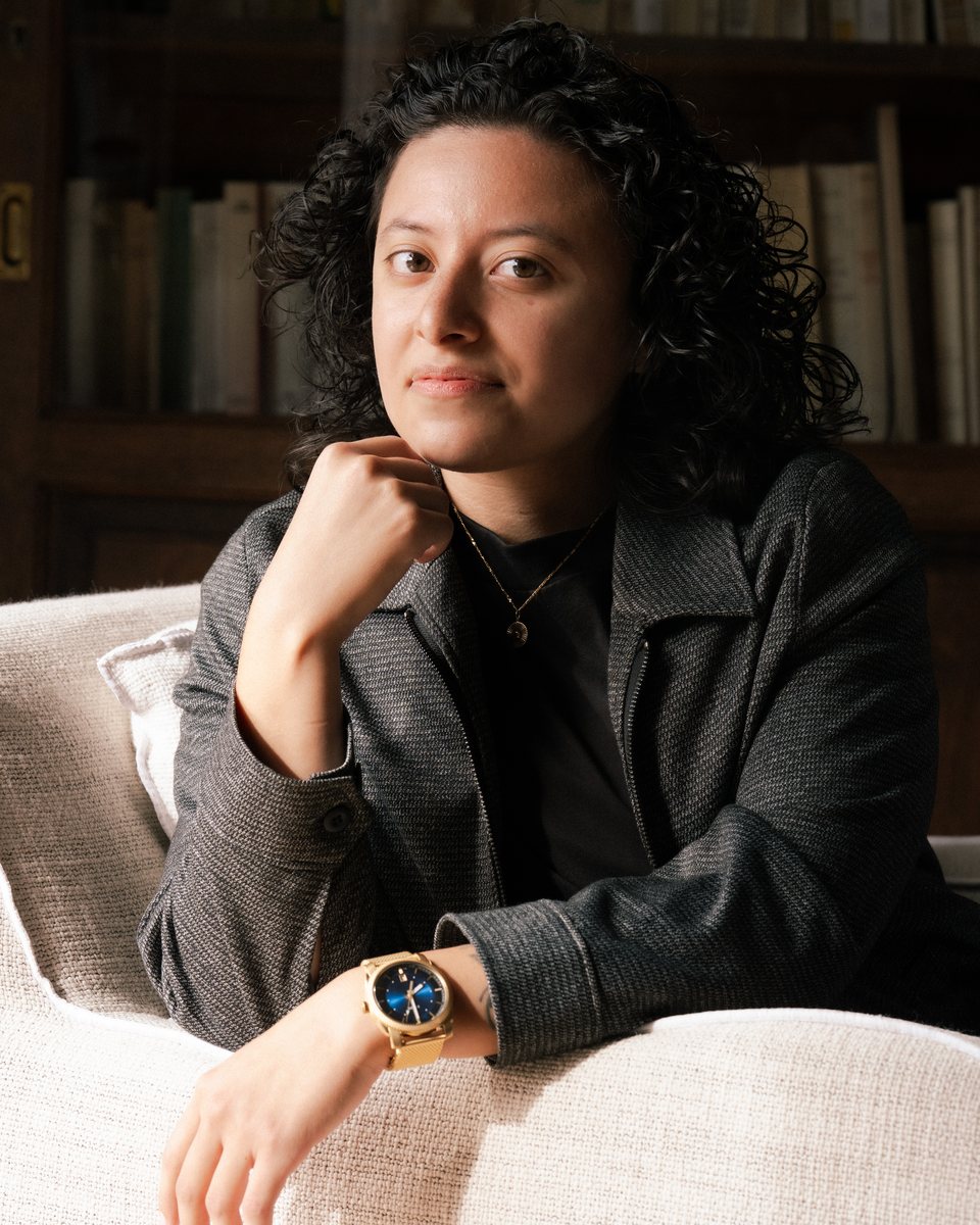 Portrait of a woman in a dark blazer seated in a library